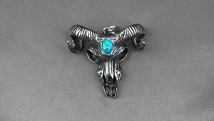Macro detail of goat skull pendant with turquoise inlay and textured spiral horns