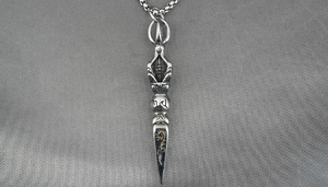 Detailed macro view of silver titanium steel Vajra pendant with sacred scripture engraving