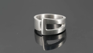 Vue macro d'une bague en acier titane brossé mat avec un design de boucle évidée géométrique