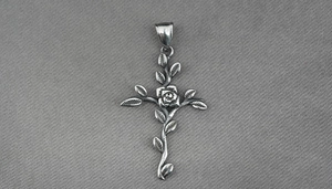 Gros plan du pendentif croix en acier titane vintage avec rose et motifs de vigne