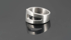 Détail de la texture en acier titane brossé et de la découpe géométrique creuse de la bague