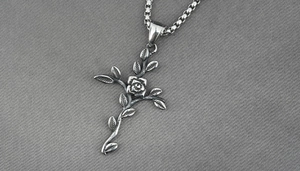 Détail du pendentif croix rose vintage sur une chaîne à mailles carrées en acier titane argenté