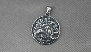 Macro shot of silver griffin relief pendant with intricate scrollwork and bail detail