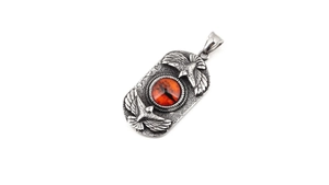 Detail of vintage steel pendant featuring dual eagles and a red devil eye center stone