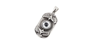 Macro view of vintage eagle and eye relief details on rectangular stainless steel pendant