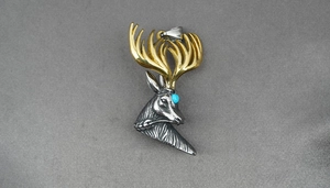 Detailed view of bicolor deer head pendant with blue turquoise eye and golden antlers