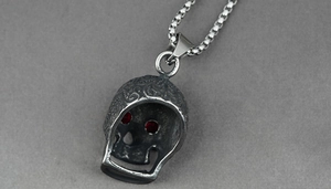 Close-up of gothic skull pendant with red rhinestone eyes and floral metal engravings