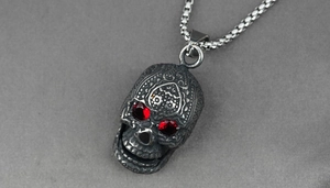 Macro shot of silver vintage skull pendant featuring red gemstone eyes and box chain