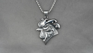 Detailed macro view of retro rooster head pendant on a stainless steel square box chain