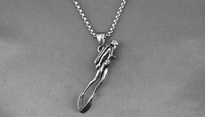 Vue détaillée du pendentif plongeur en acier titane argenté avec chaîne sur tissu gris