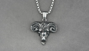 Detailed close-up of a vintage ram head pendant with spiral horns on a steel chain