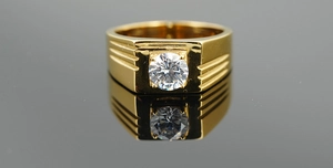 Close-up of golden men's ring with central round diamond and side groove textures