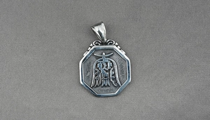 Macro detail of silver octagonal Tai Chi pendant with relief engraving on fabric