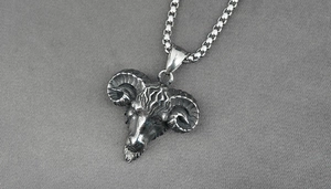 Macro shot of retro stainless steel ram head pendant with detailed spiral horns and chain
