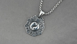 Macro detail of vintage Tai Chi Yin Yang pendant on a stainless steel bead chain