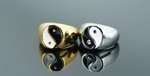 Macro view of gold and silver Tai Chi Yin Yang rings reflected on a dark surface