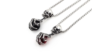 Detailed view of punk skeleton pendants with black and red gems on steel box chains