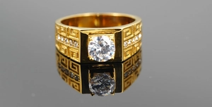 Macro shot of gold wide band ring featuring Greek Key engraving and large round zircon