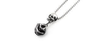 Detailed macro view of a vintage skull pendant gripping a polished black stone bead
