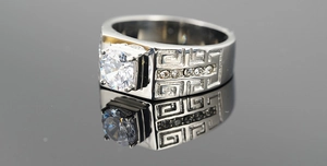 Macro shot of silver titanium ring featuring Greek Key patterns and a large center stone