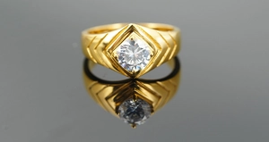 Detailed close-up of a gold titanium ring featuring a large round brilliant-cut gemstone