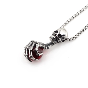Gothic skull pendant necklace with red gem held by skeletal hand on box chain