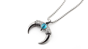 Vue macro du pendentif croissant argent vintage avec œil de turquoise sur chaîne à maillons