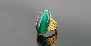Dettaglio macro di anello vintage dorato con pietra occhio di gatto verde e incisione