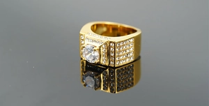 Gros plan d'une bague large dorée pour homme avec pierre centrale et pavage brillant