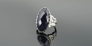 Dettaglio anello vintage in acciaio con pietra occhio di gatto blu e intaglio floreale