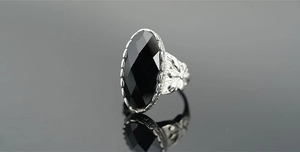 Dettaglio anello vintage in argento con gemma nera ovale e incisioni floreali