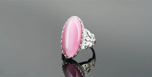 Macro di anello vintage in argento con occhio di gatto rosa e dettagli floreali