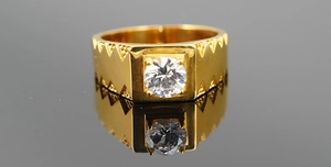 Gros plan d'une bague en titane doré avec zircone ronde et motifs géométriques gravés