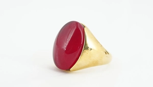 Dettaglio macro di pietra cabochon rossa ovale su anello a fascia in acciaio dorato