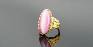 Vista macro dell'anello con pietra occhio di gatto rosa e fascia dorata con fiori