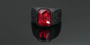 Vista macro de una gema roja rectangular en un anillo negro mate con patrones grabados