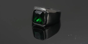 Detalle macro de una gema verde talla esmeralda en un anillo de metal negro pulido