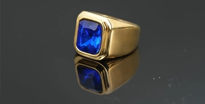 Detalle de una gema azul rectangular en un anillo de oro pulido con reflejo espejo