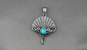Macro detail of vintage turquoise fan pendant with oxidized steel texture and intricate engraving