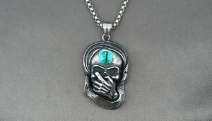 Vue détaillée du pendentif tête de mort punk avec pierre verte et chaîne gourmette sur soie