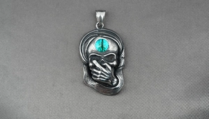 Détail macro du pendentif crâne gothique avec œil de dragon et main sur la bouche