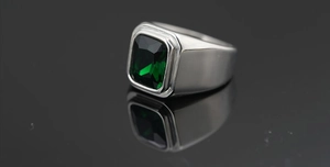 Primer plano de anillo para hombre plateado con gran gema verde rectangular brillante