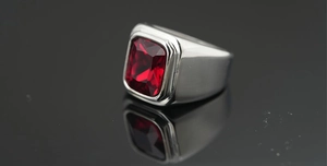 Vista detallada de un anillo de plata para hombre con gema roja sobre fondo oscuro
