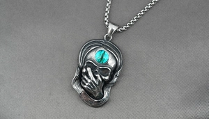 Détail macro du pendentif crâne gothique en acier vintage avec pierre œil de chat verte