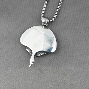 Polished silver stingray pendant necklace with a box chain on a grey textured background