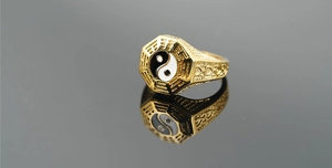 Macro shot of gold octagonal Tai Chi ring showing intricate Bagua symbols and enamel inlay