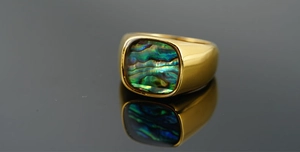 Macro shot of gold stainless steel ring featuring a vibrant abalone shell inlay