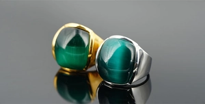 Vista macro di anelli in acciaio al titanio con gemme verdi in finiture oro e argento