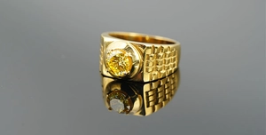 Macro shot of gold-plated titanium ring with yellow zircon and grid textured band