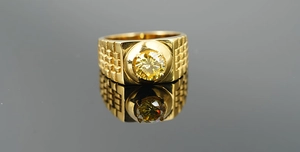 Macro shot of gold-plated titanium ring with yellow round gemstone and link-style band